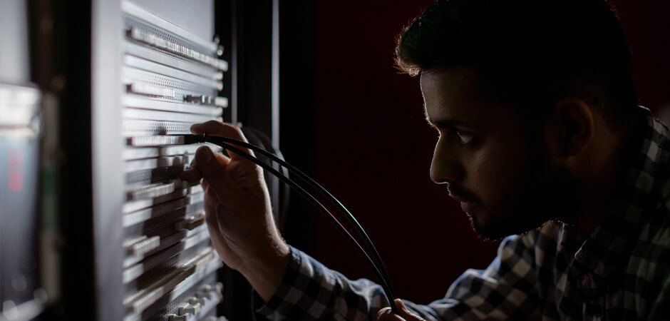 man plugging cable into server