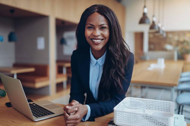 Woman smiling standing at table with computer